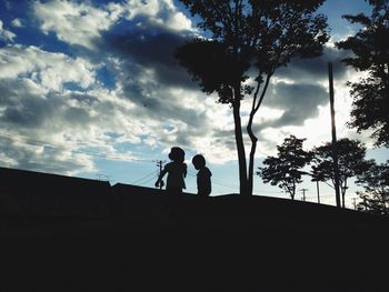 Silhouette of trees against cloudy sky