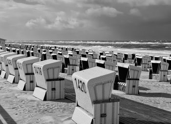 Hooded chairs on beach against sky