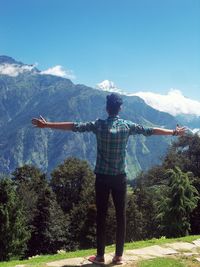 Man with arms outstretched against mountain range