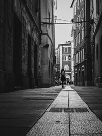 People walking on footpath amidst buildings in city