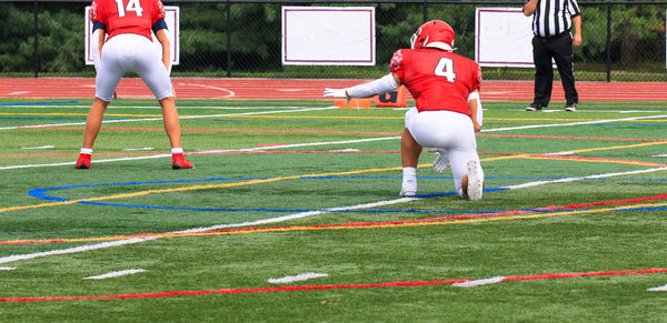 The holder is ready for the ball during a field goal on a turf field.