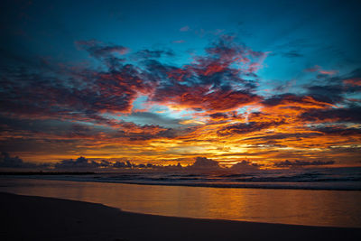 Scenic view of sea against dramatic sky during sunset