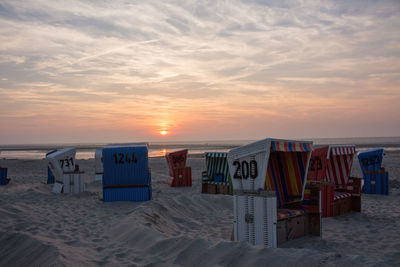 Empty chairs at beach during sunset