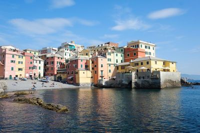 Buildings by sea against blue sky