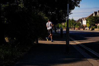 Full length of man running on footpath by tree