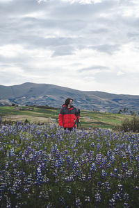 People on purple flowering plants on land against sky