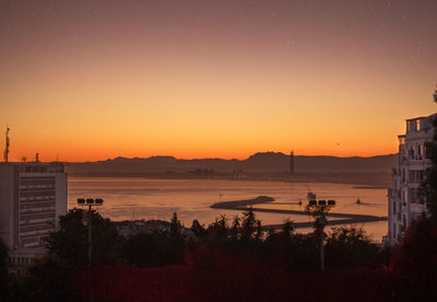 Scenic view of beach and buildings against sky during sunset