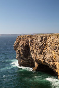 Scenic view of rocks in sea against clear sky