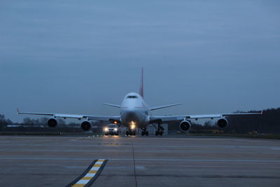 Airplane on runway against sky at dusk