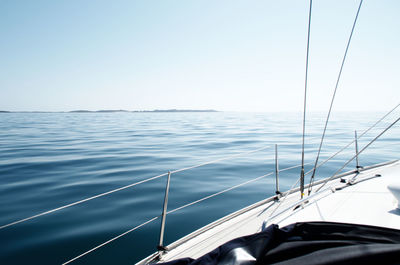 Close-up of sailboat sailing on sea against clear sky