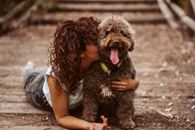 Woman embracing dog lying on road