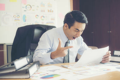 Happy businessman looking at paper in office