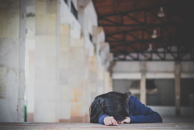 Sad woman lying on floor in building