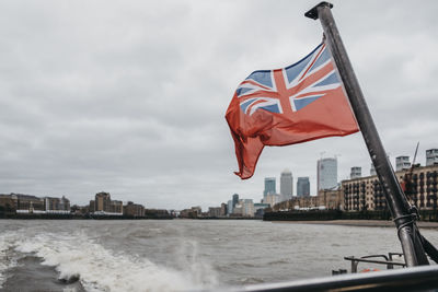 British flag waving on boat in river against sky