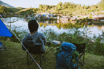 Rear view of man sitting by lake