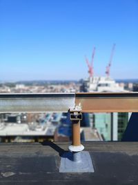 Close-up of metallic railing against buildings and clear sky