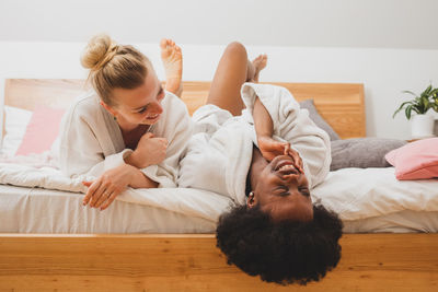 Smiling females friends lying on bed at hotel