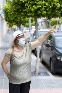 Midsection of woman standing by car on street