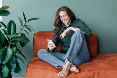 Portrait of young woman sitting on sofa at home