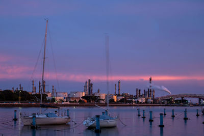 Sailboats moored at harbor during sunset