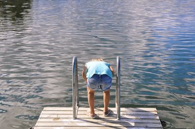 Rear view of man standing on pier over lake