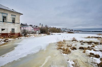 Buildings by sea against sky during winter