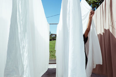 Close-up of clothes hanging on clothesline against sky