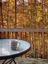 Coffee cup on table against trees in forest during autumn