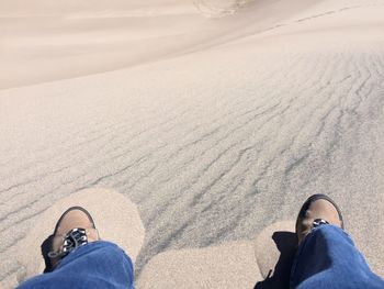 Low section of man standing on sand at beach