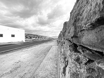 Empty road amidst buildings against sky