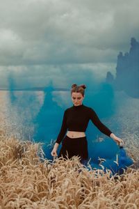 Woman with blue distress flare standing on field