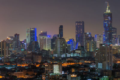 Illuminated buildings in city against sky at night