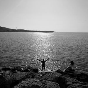 Rear view of man standing in sea against clear sky