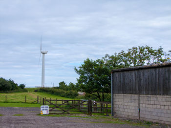 Trees on field against cloudy sky