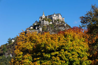 Low angle view of autumn trees and building against sky