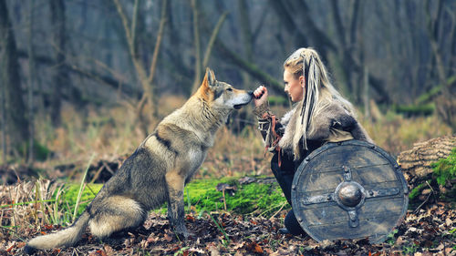 Woman looking at wolf in forest