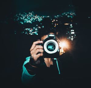 Man photographing through digital camera at night