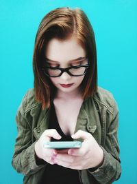 Teenage girl using mobile phone against blue background