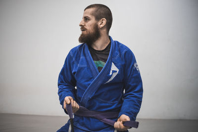 Young man wearing karate uniform against wall