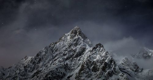 Low angle view of snowcapped mountains against sky at night