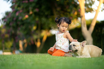 Cute girl with dog sitting at park