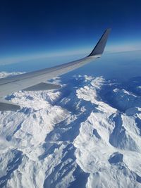 Aerial view of snowcapped mountain against blue sky