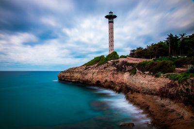 Lighthouse by sea against sky