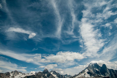 Low angle view of snowcapped mountains against blue sky