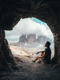 Side view of man sitting on rock