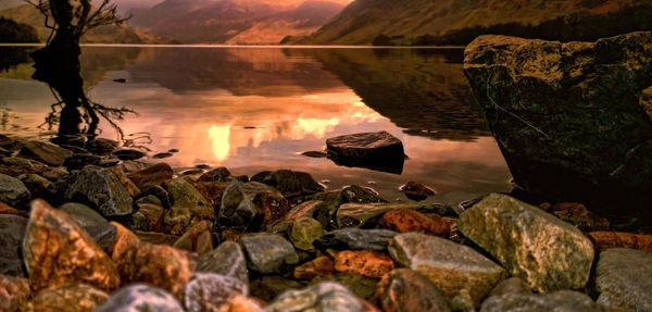 Panoramic shot of rocks at lakeshore during sunset