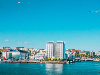 Sea by buildings against blue sky