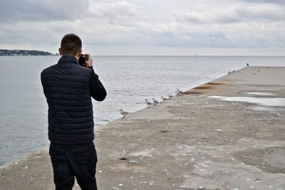 Rear view of man photographing sea