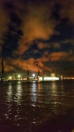 Silhouette harbor against sky at night