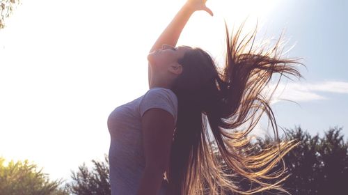 Woman with tousled hair against sky